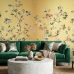 Floral bird wallpaper design with yellow background in modern living room featuring teal velvet sofa, decorative cushions and elegant home décor
