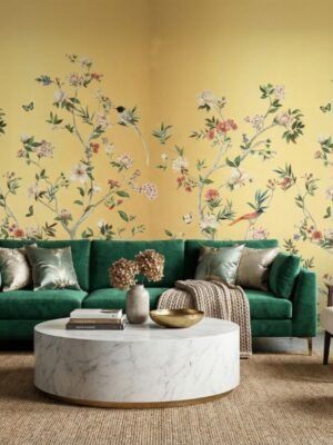Floral bird wallpaper design with yellow background in modern living room featuring teal velvet sofa, decorative cushions and elegant home décor