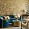 Elegant golden yellow floral mural wallpaper with delicate tree branches, blooming flowers, and birds in a luxury living room with blush seating and ornate mirror