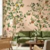 Elegant botanical mural wallpaper featuring hand-painted citrus trees with oranges, lemons, and delicate birds on a soft peach background, styled in a modern living room with a green velvet sofa and natural wood furniture.