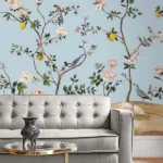 Elegant floral bird mural wallpaper with pastel blue background, featuring blooming branches, lemons, and colorful birds in a classic vintage style living room setting.